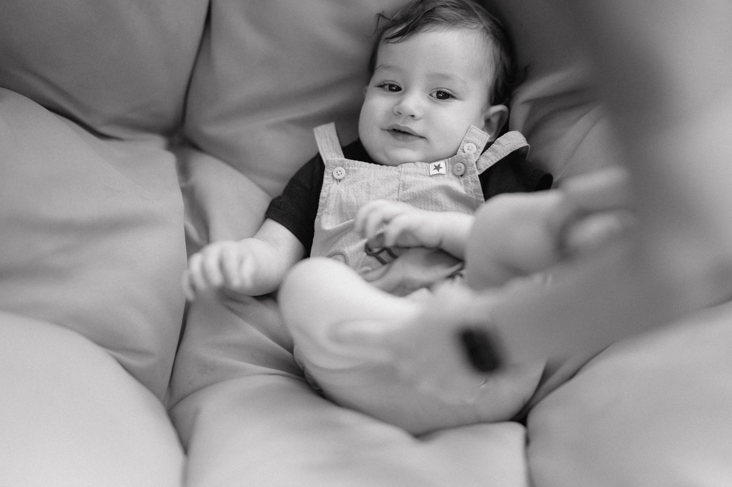 Black and white image series showing tender moments of a newborn baby being cradled and held by caring hands.