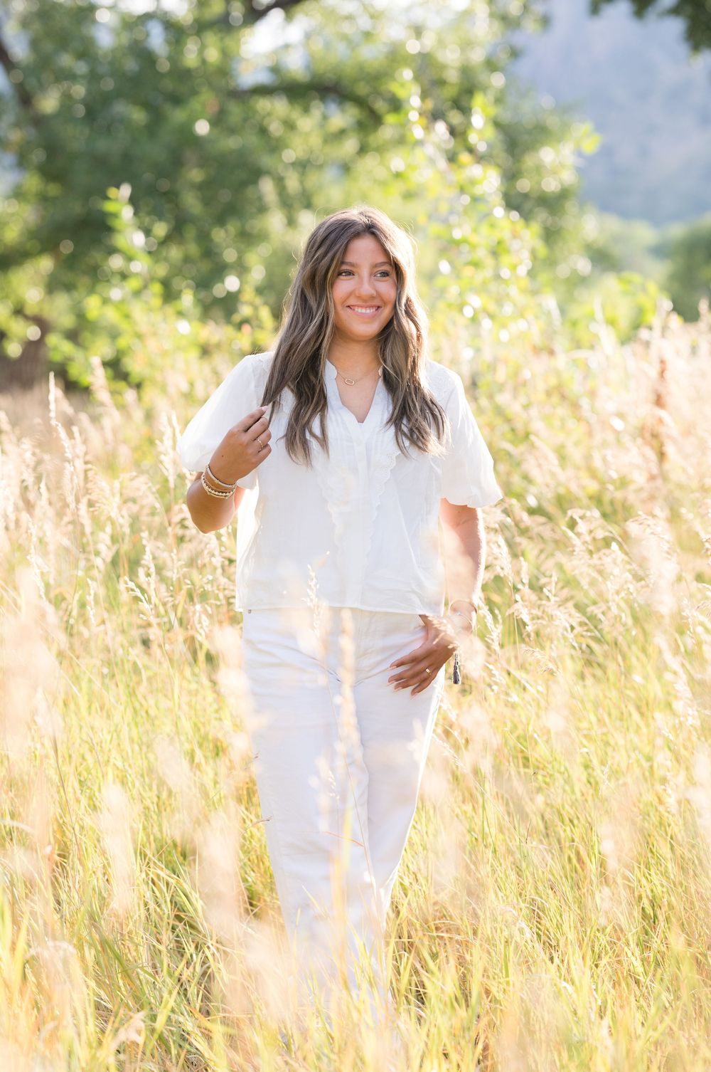 Lifestyle portrait in white outfit standing in golden summer field with natural sunlit background.