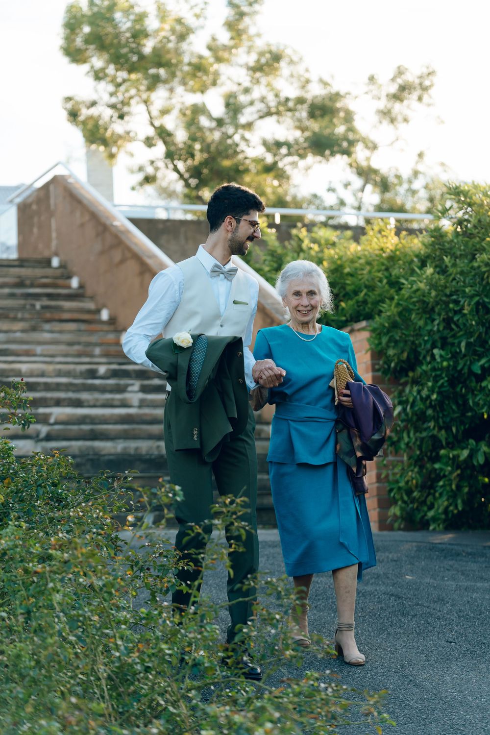 A touching moment of assistance and care in a garden setting with stone steps in the background.