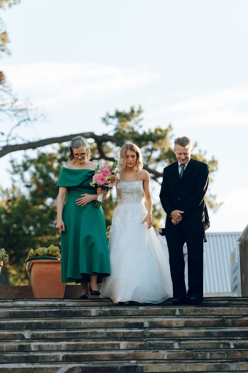 A wedding party descends stone steps outdoors during a ceremony.