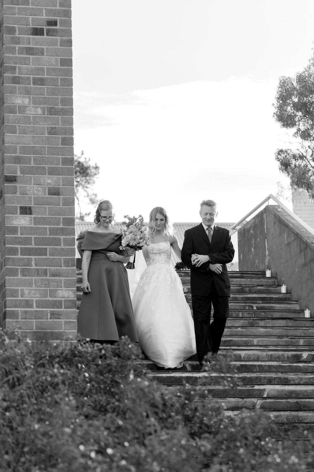 A black and white photograph of a wedding party walking down stone steps.