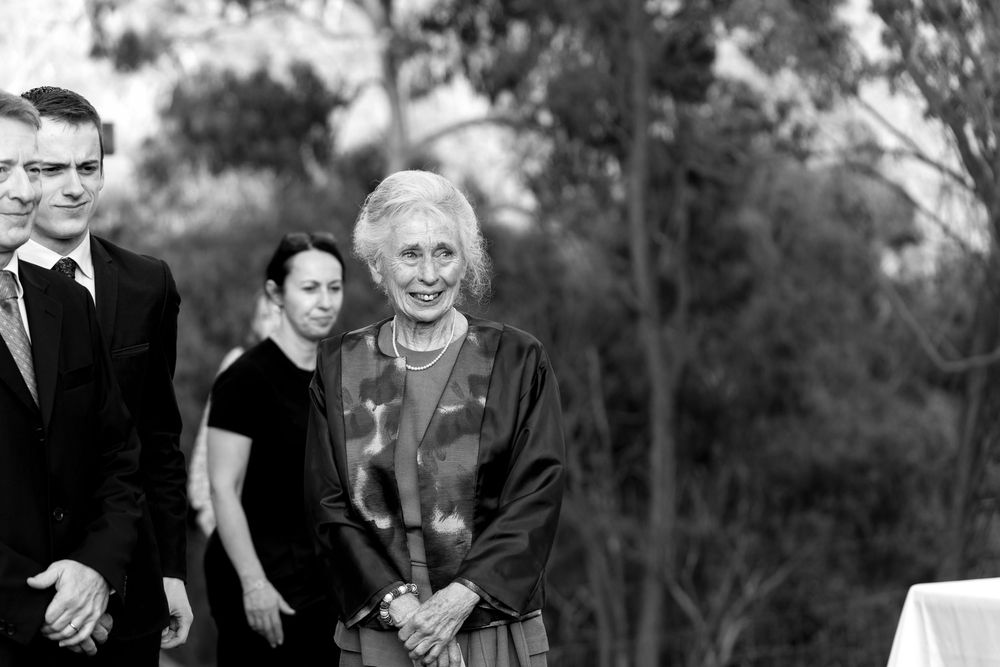 A candid black and white photograph at an outdoor wedding venue.