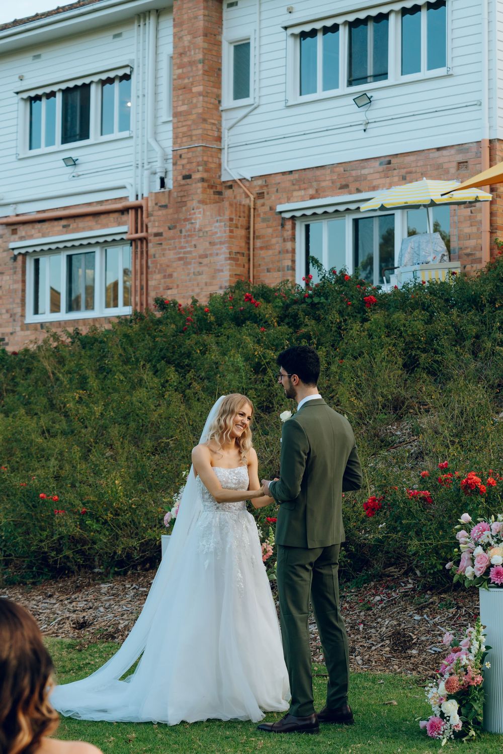 A wedding couple shares an intimate moment in front of a brick and white building.