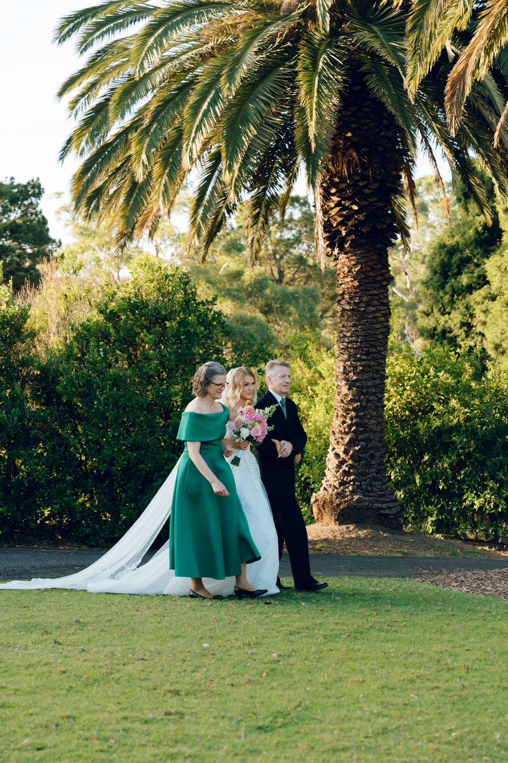 Wedding party poses under a majestic palm tree during an outdoor ceremony.