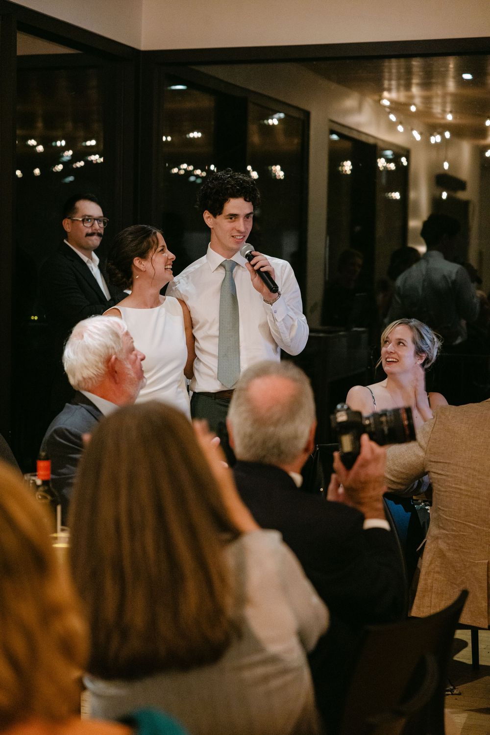 Wedding reception guests dancing and celebrating together in a dimly lit venue with joyful atmosphere.