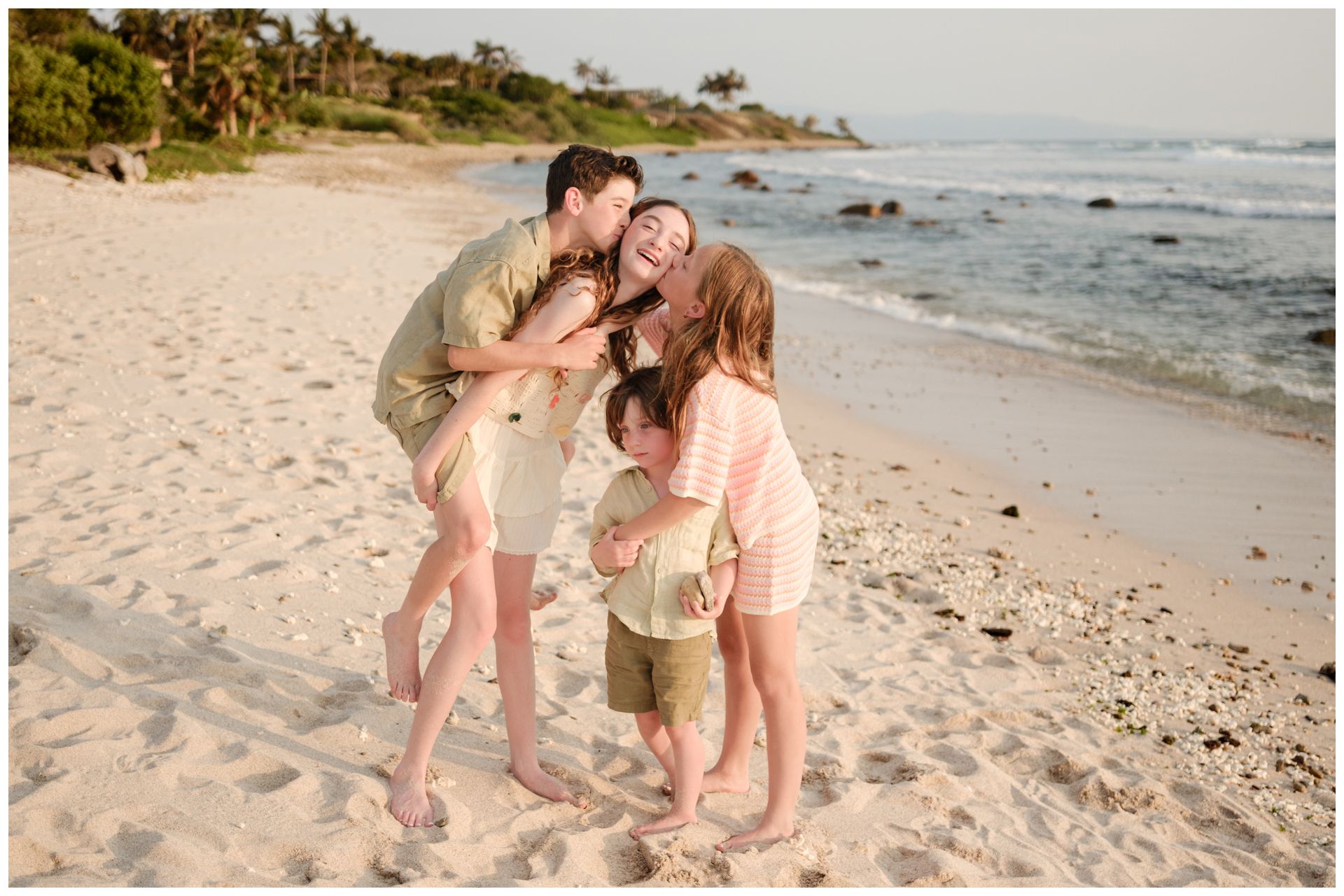 A loving family moment captured on a scenic Hawaiian beach at sunset.