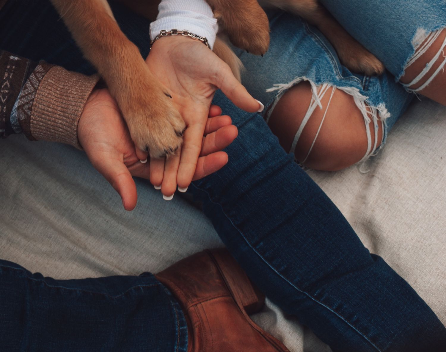 Close up of hands holding each other tenderly on blue denim.