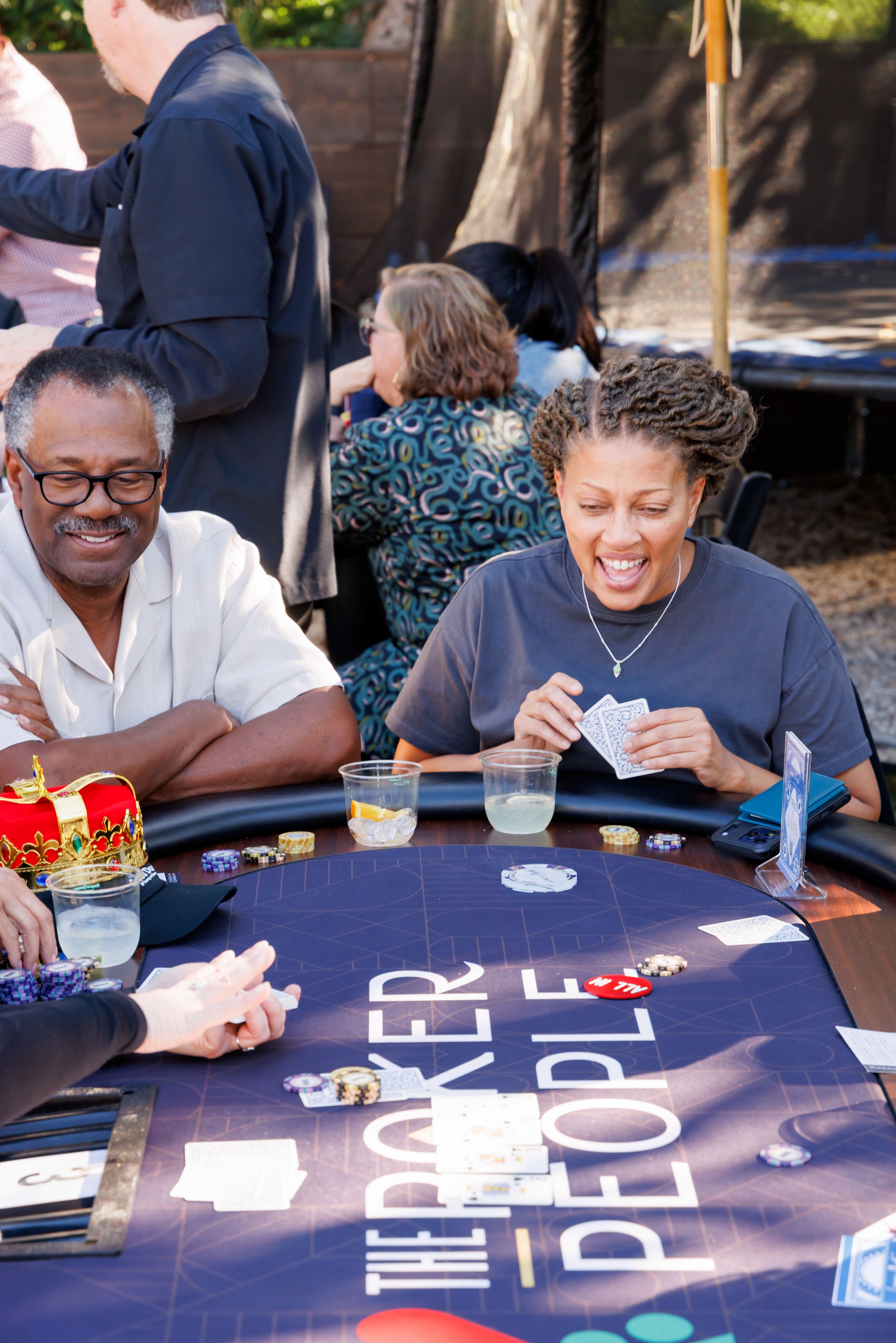 Two people laughing and playing poker at outdoor casino-themed party event.