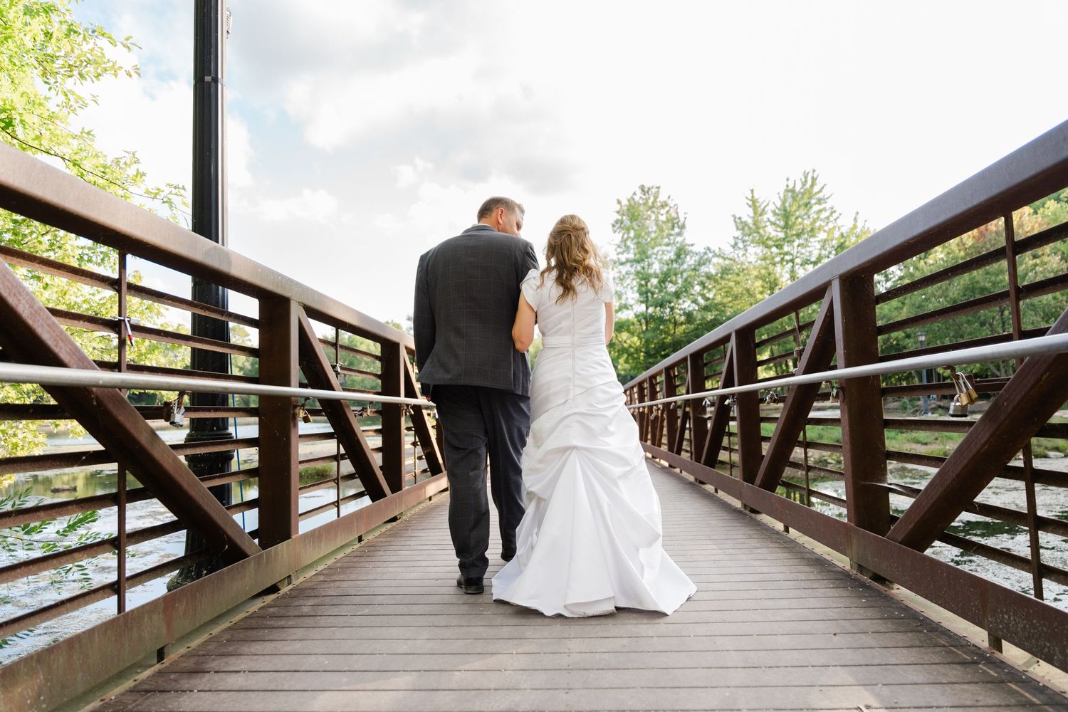 A sequence of romantic wedding photos showing a couple walking along a wooden bridge surrounded by greenery.