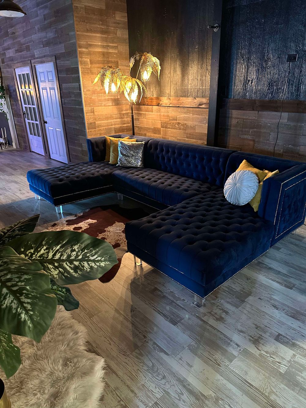 Modern lounge area with navy blue velvet couch, wood paneled walls, and ambient lighting.