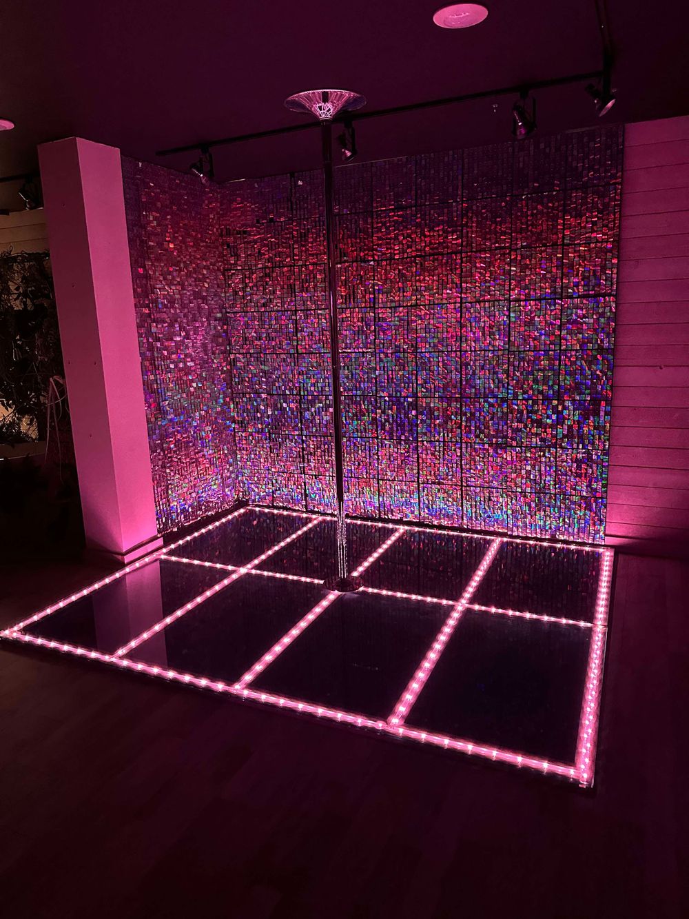 Pink and blue neon-lit dance floor space with geometric lighting pattern design.