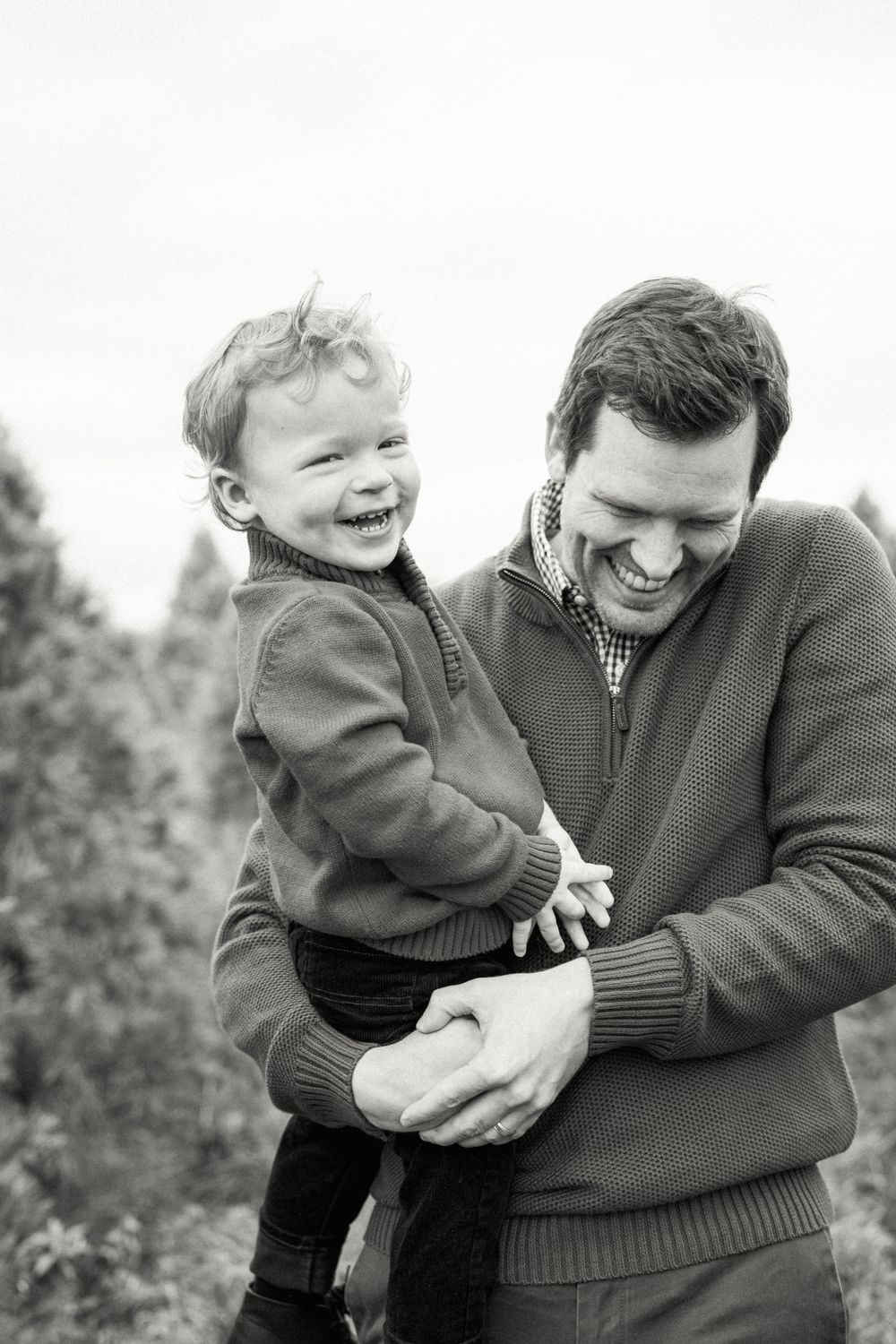 A heartwarming black and white photo of playful moments between a parent and child outdoors.