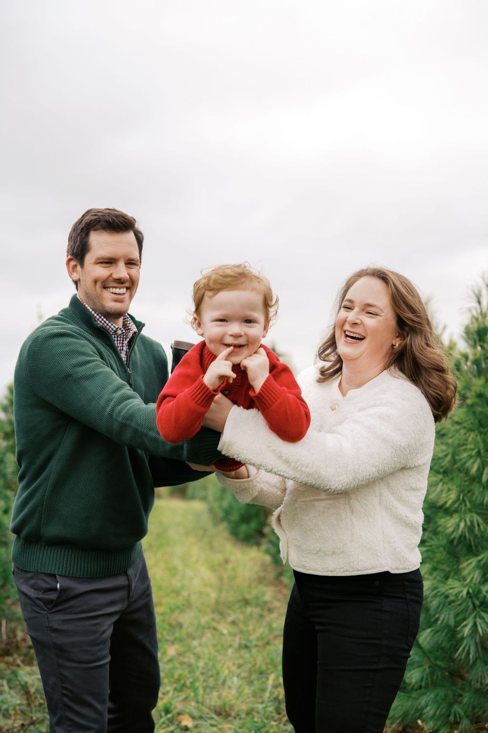 Joyful family moment captured at a Christmas tree farm with everyone laughing together.