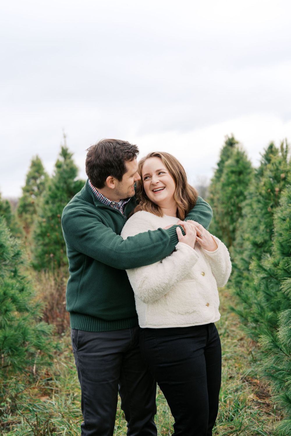 Couple sharing an intimate moment while embracing among evergreen trees.