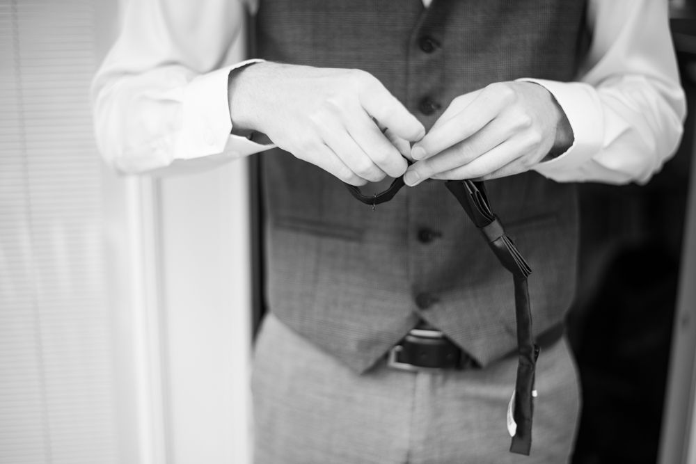 Black and white close-up of hands adjusting a tie or bowtie.