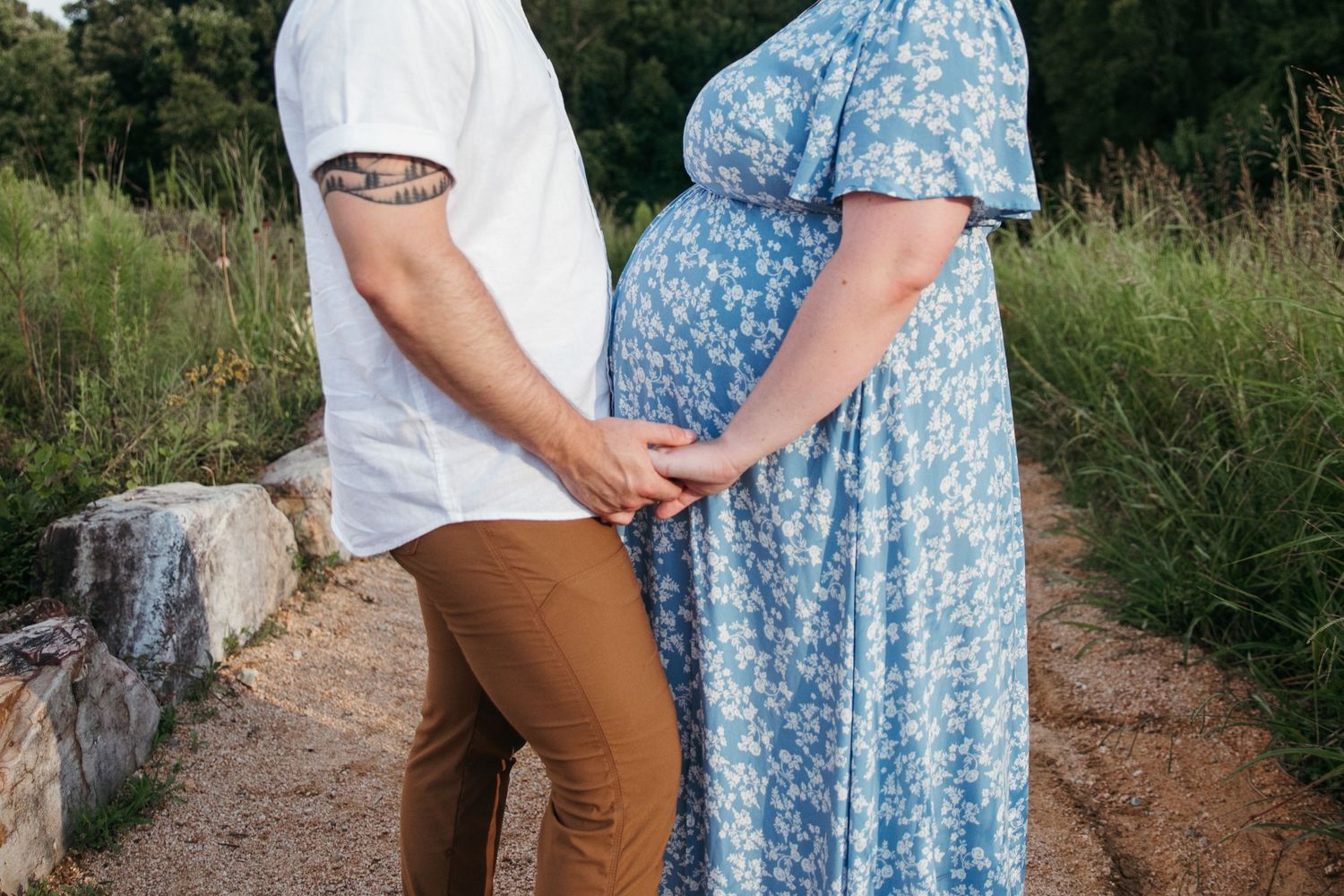 Couple holding hands in casual outdoor setting, with person wearing floral blue dress.