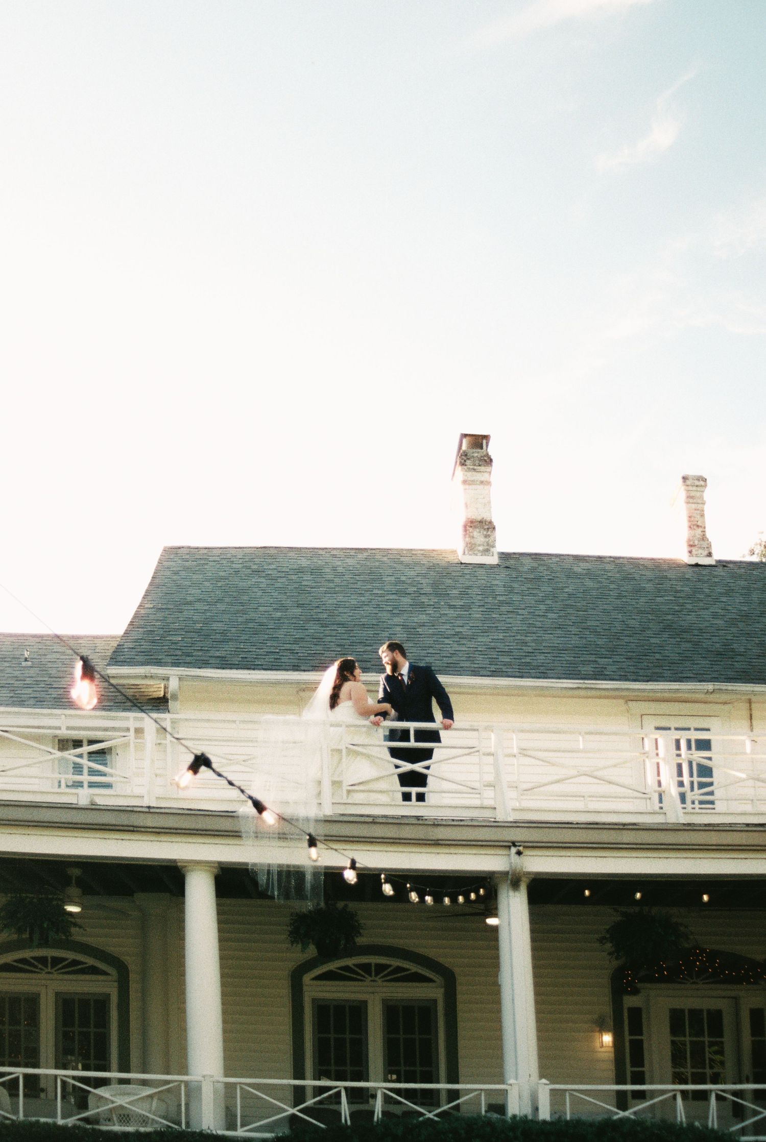 A sequence of four photos showing a white colonial-style building exterior with columns and string lights at dusk.