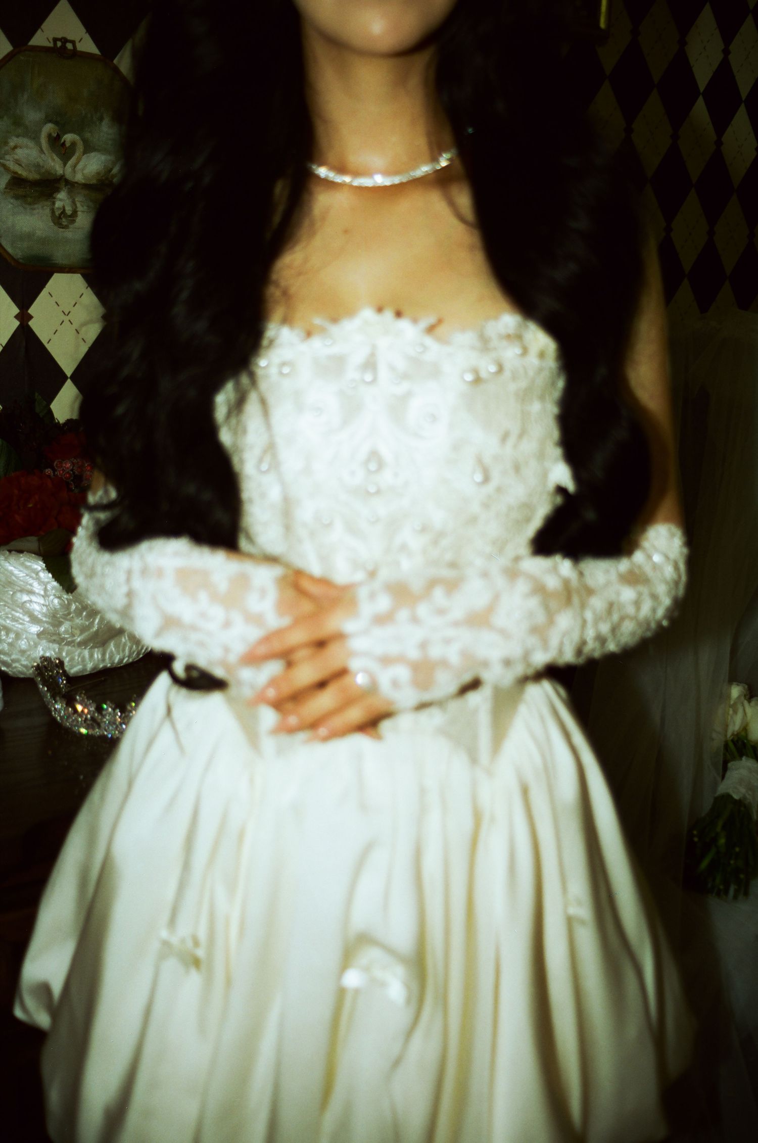 Bride in strapless white lace wedding gown with floral appliques, lace gloves, and pearl necklace.