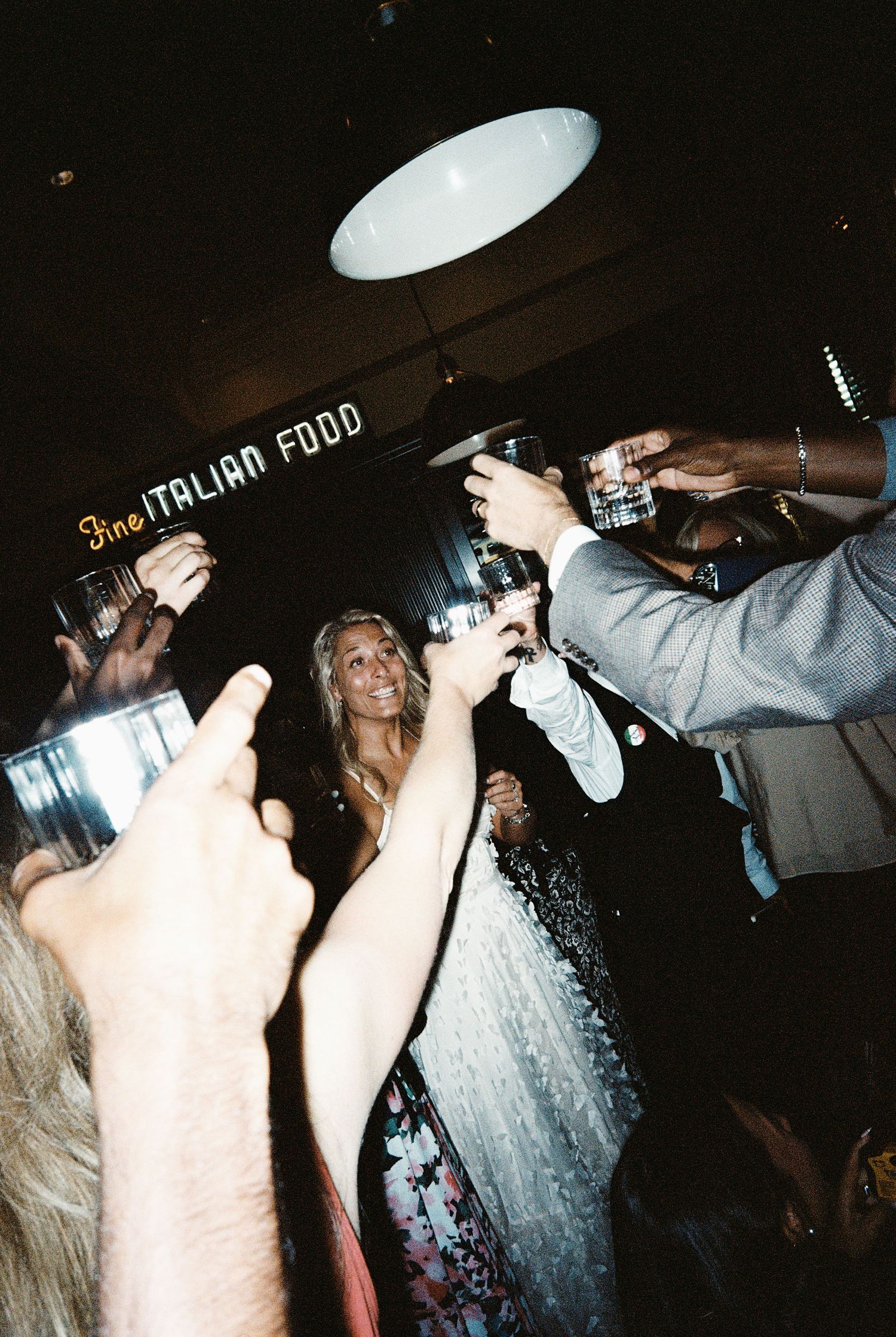 Group toasting drinks at a Fine Italian Food restaurant celebration with smiling guests raising glasses.