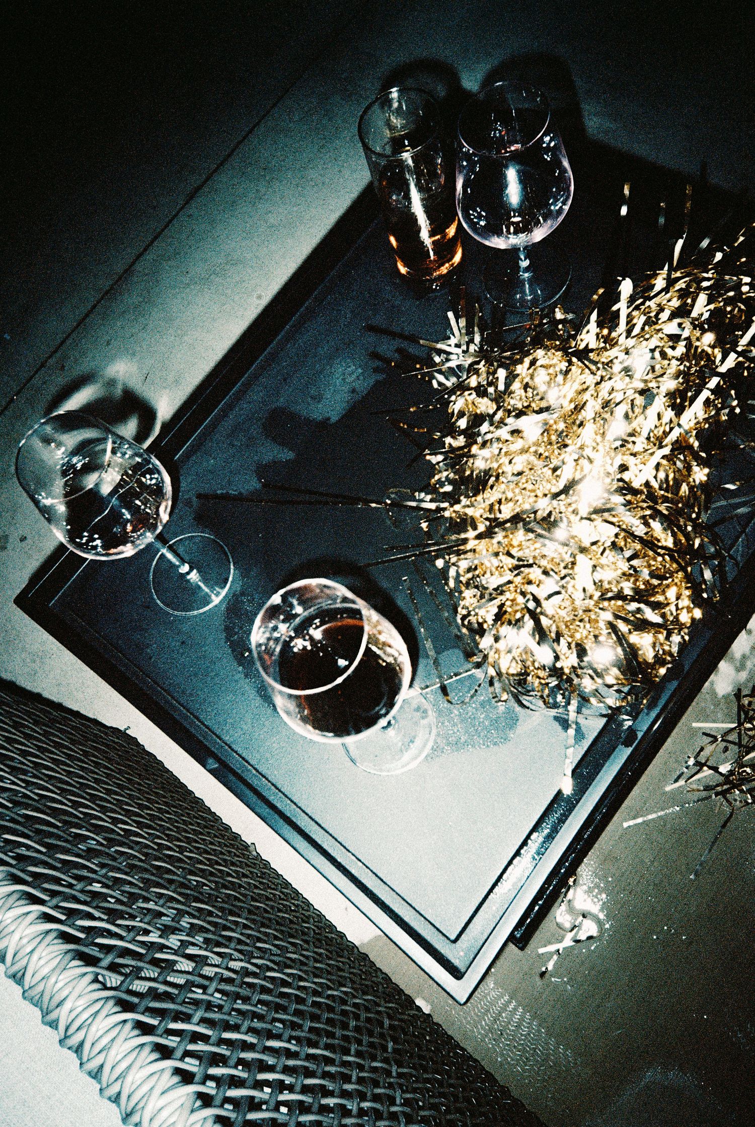 Overhead view of wine glasses and sparkling gold tinsel on a dark tray at a festive party celebration.