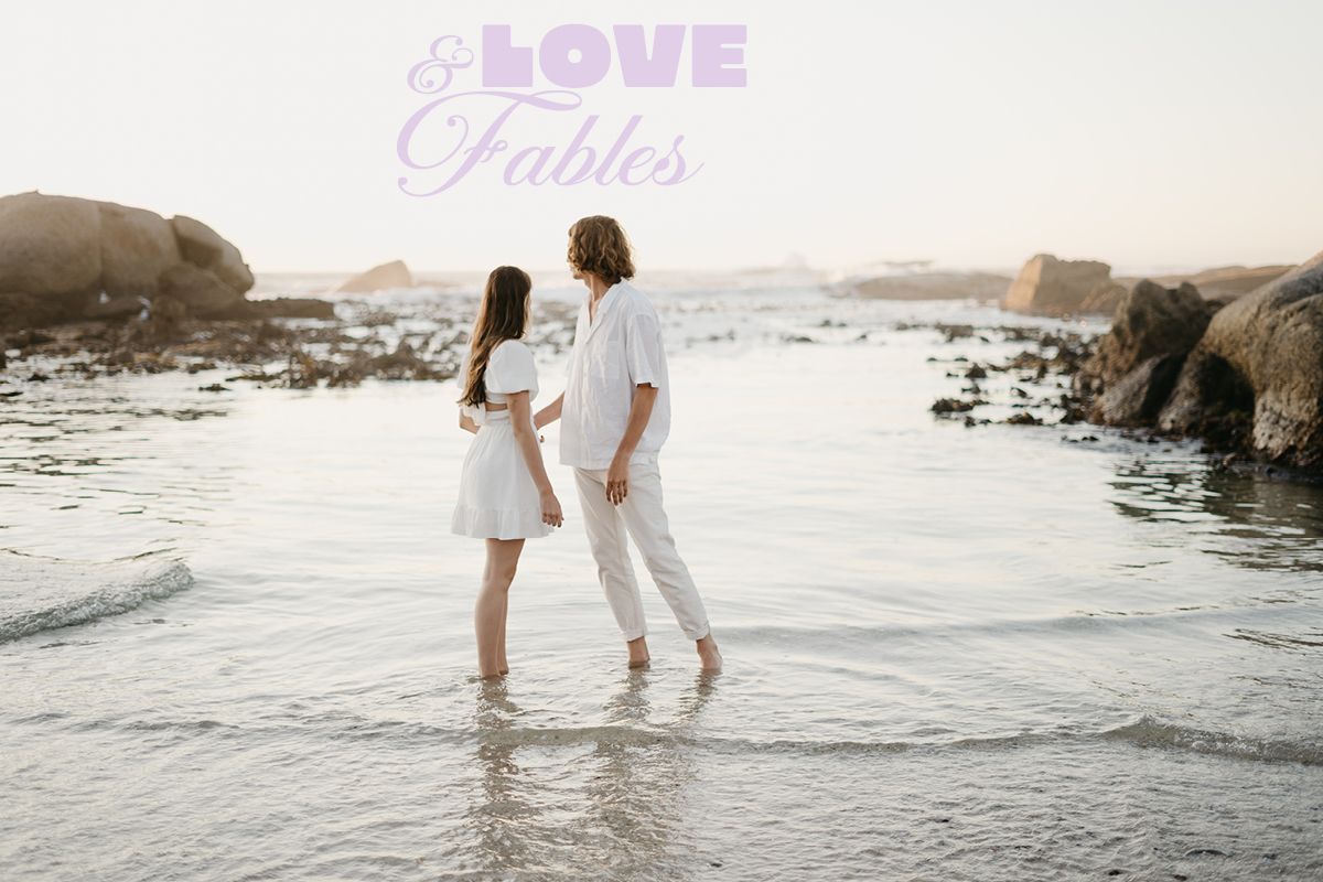 Couple in love surrounded by the beautiful western cape beach scenery with mountains and water in back at Clifton 4th Beach in South Africa