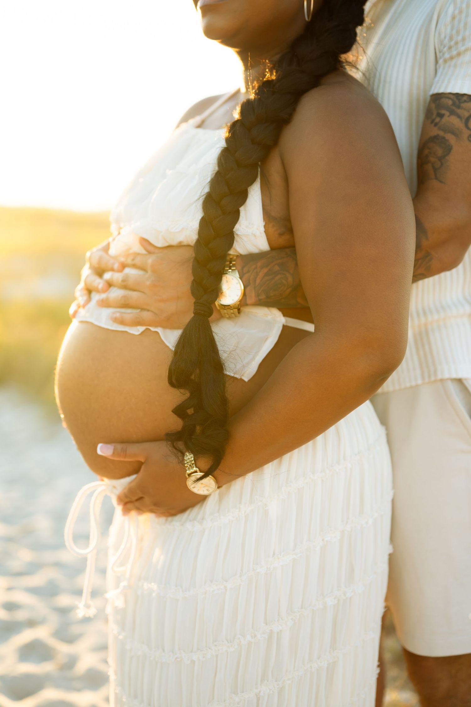 Couple holding ultrasound photos while wearing white and green outfits outdoors.