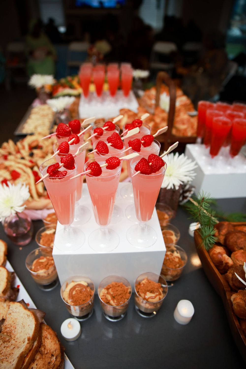 Elegant dessert display featuring pink drinks topped with raspberries and small bites.