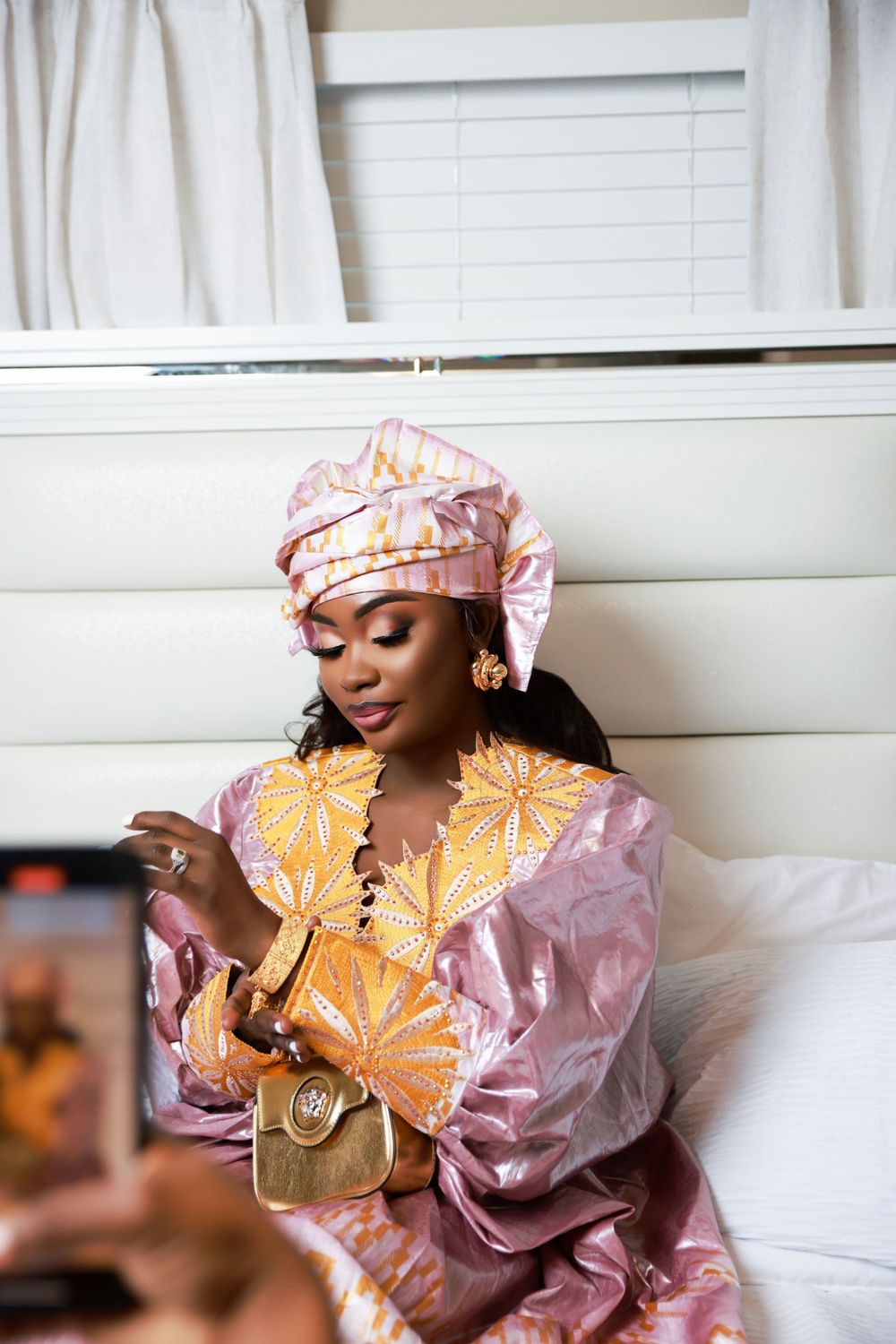 Traditional African attire in pink and gold with matching headwrap and designer purse.