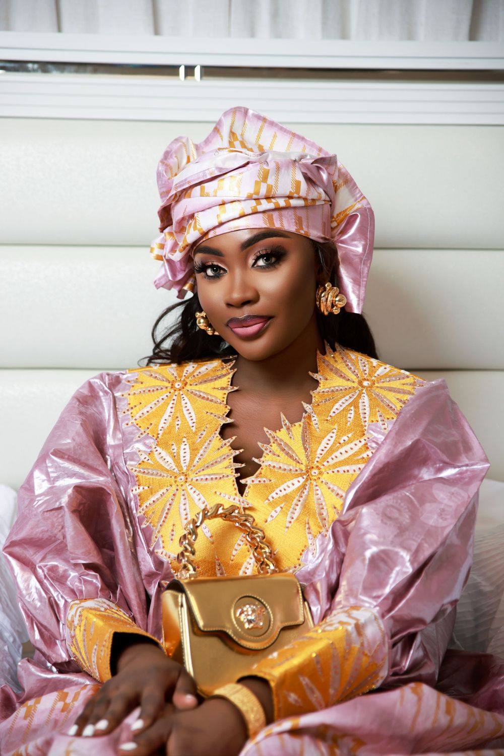 Elegant pink and gold traditional African dress with matching headwrap and accessories.