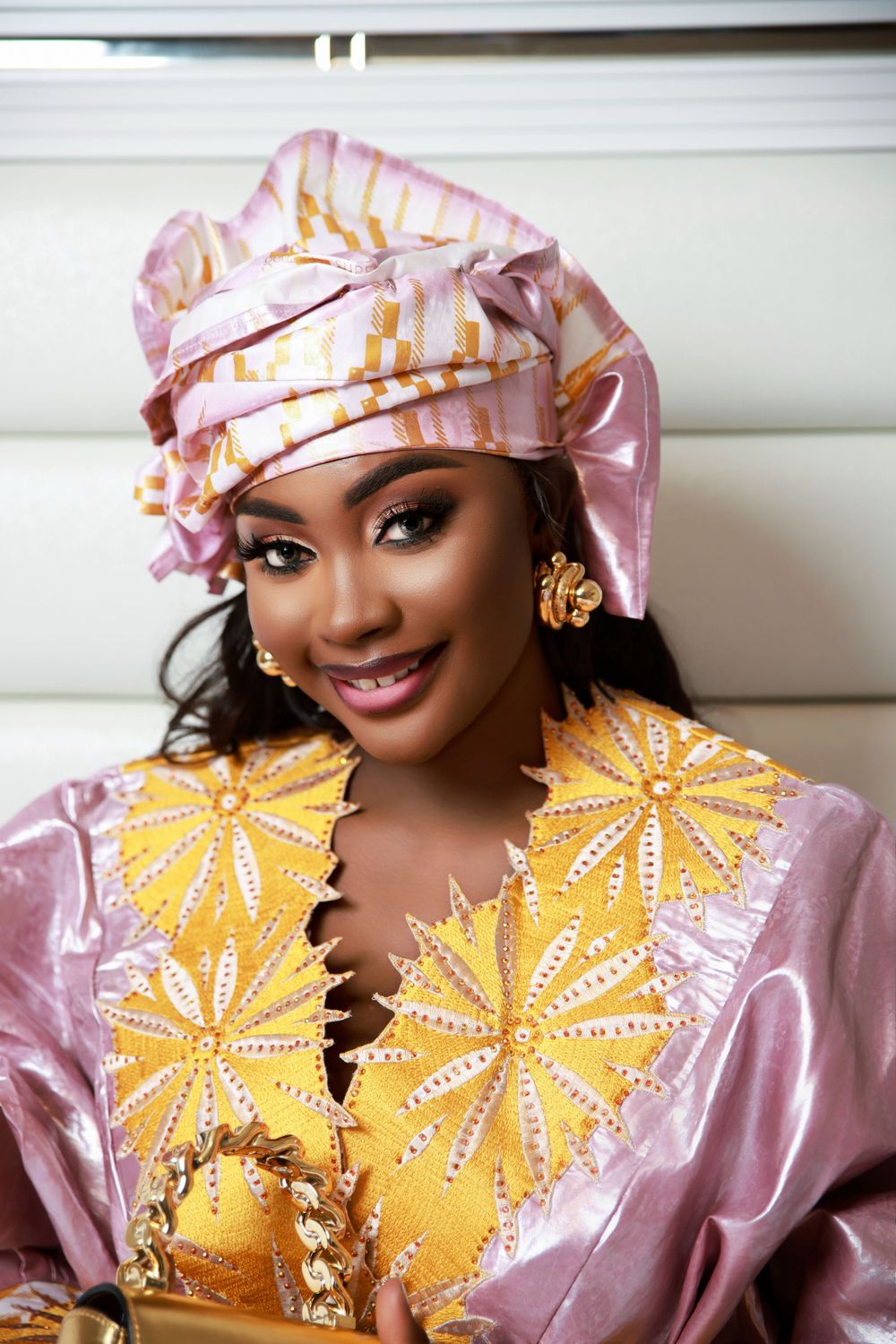 Traditional African fashion photoshoot featuring pink and yellow attire with elegant gold accessories.