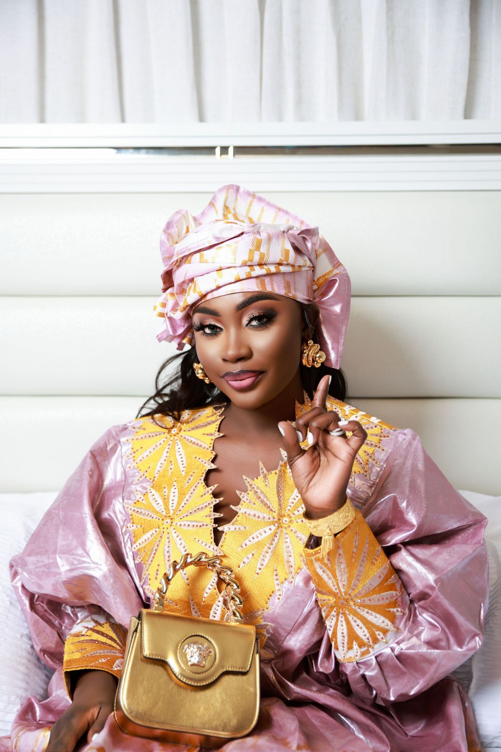 Fashion portrait showcasing traditional African attire in pink and gold with matching accessories.