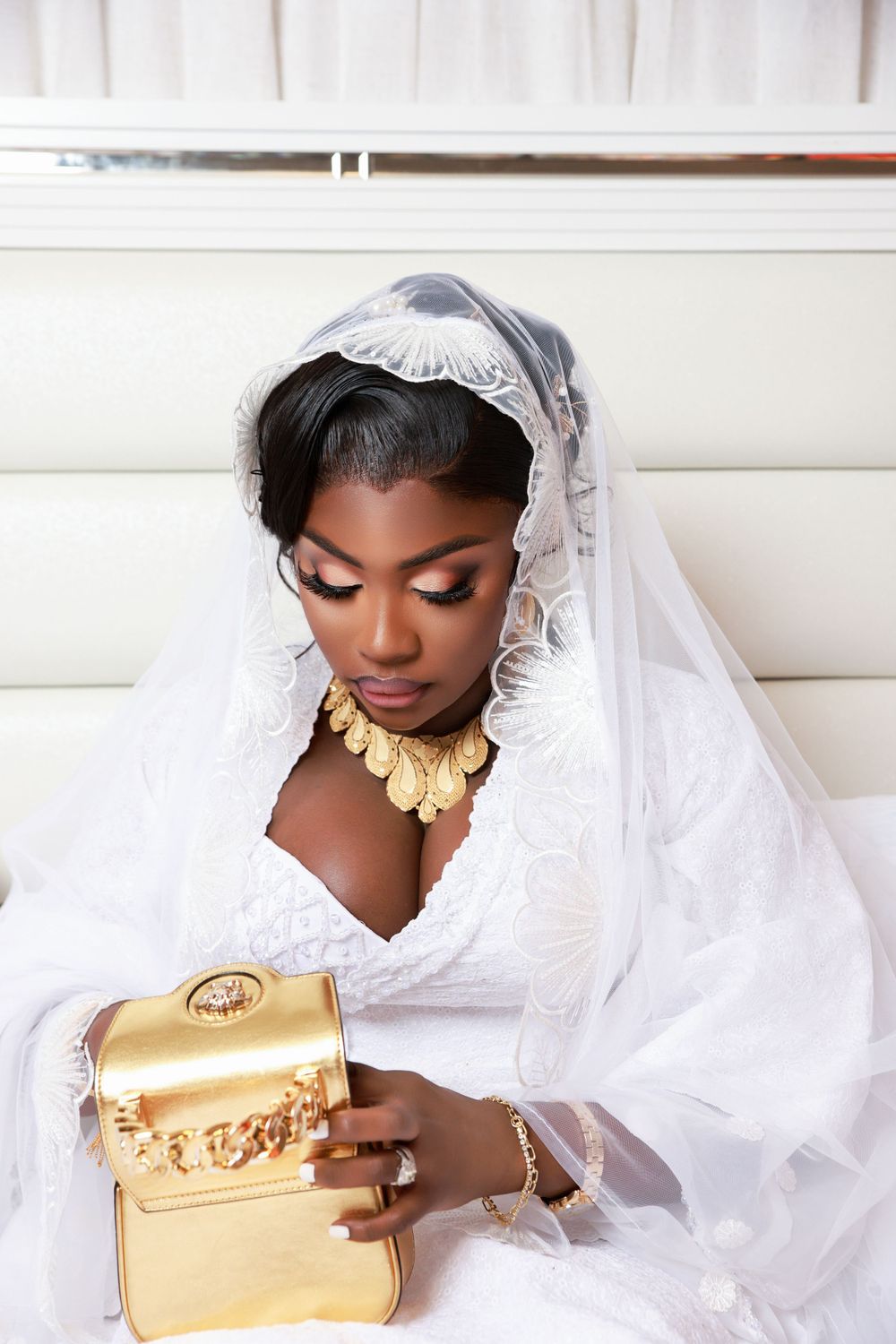 Bridal portrait in classic white dress and veil with gold accessories.