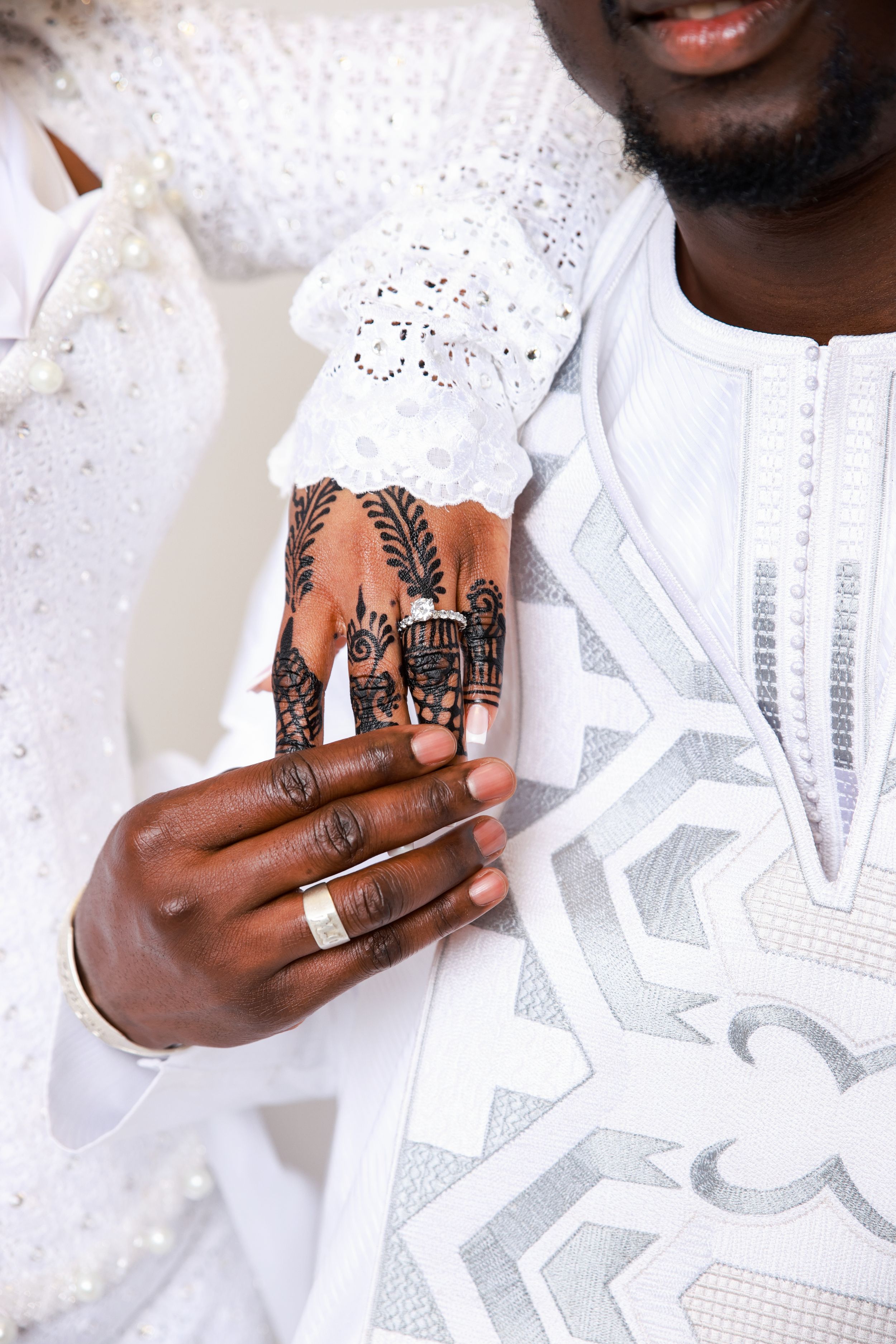 Close-up of hands with henna designs wearing traditional white clothing.