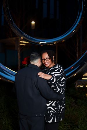 A romantic evening moment captured under a large blue circular architectural feature.