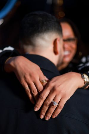 Close-up shot of hands embracing showing a sparkling engagement ring.