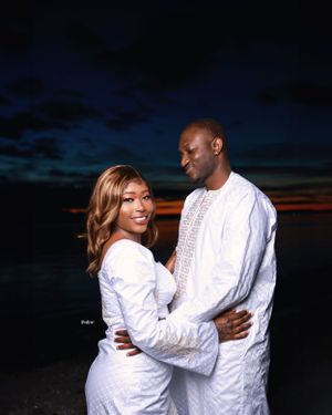 Intimate beach photo session at sunset with couple wearing coordinated white ensembles.