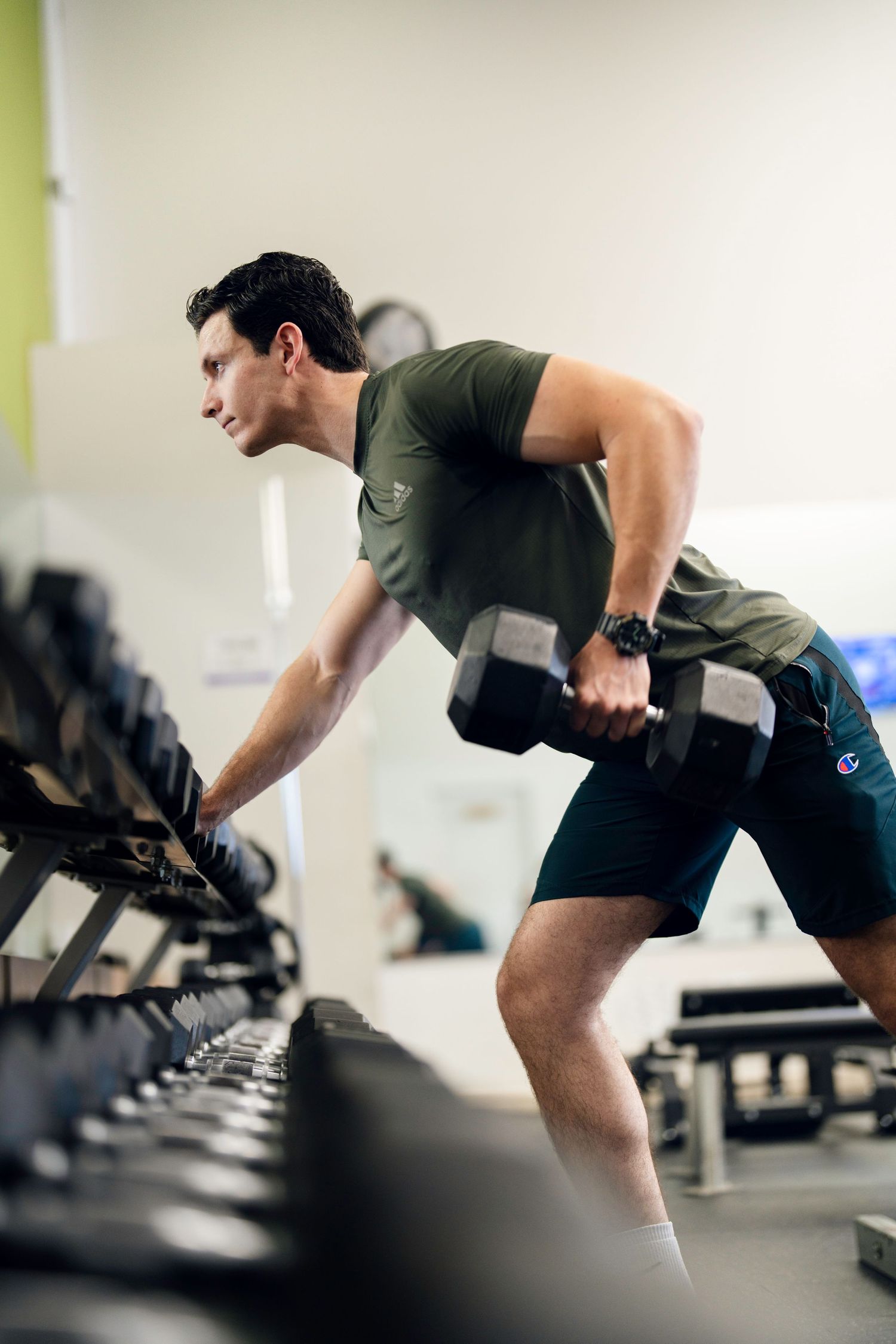 Person exercising with dumbbells in a modern gym setting.