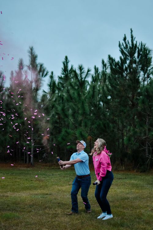 Two people enjoying a colorful confetti celebration against a backdrop of pine trees.