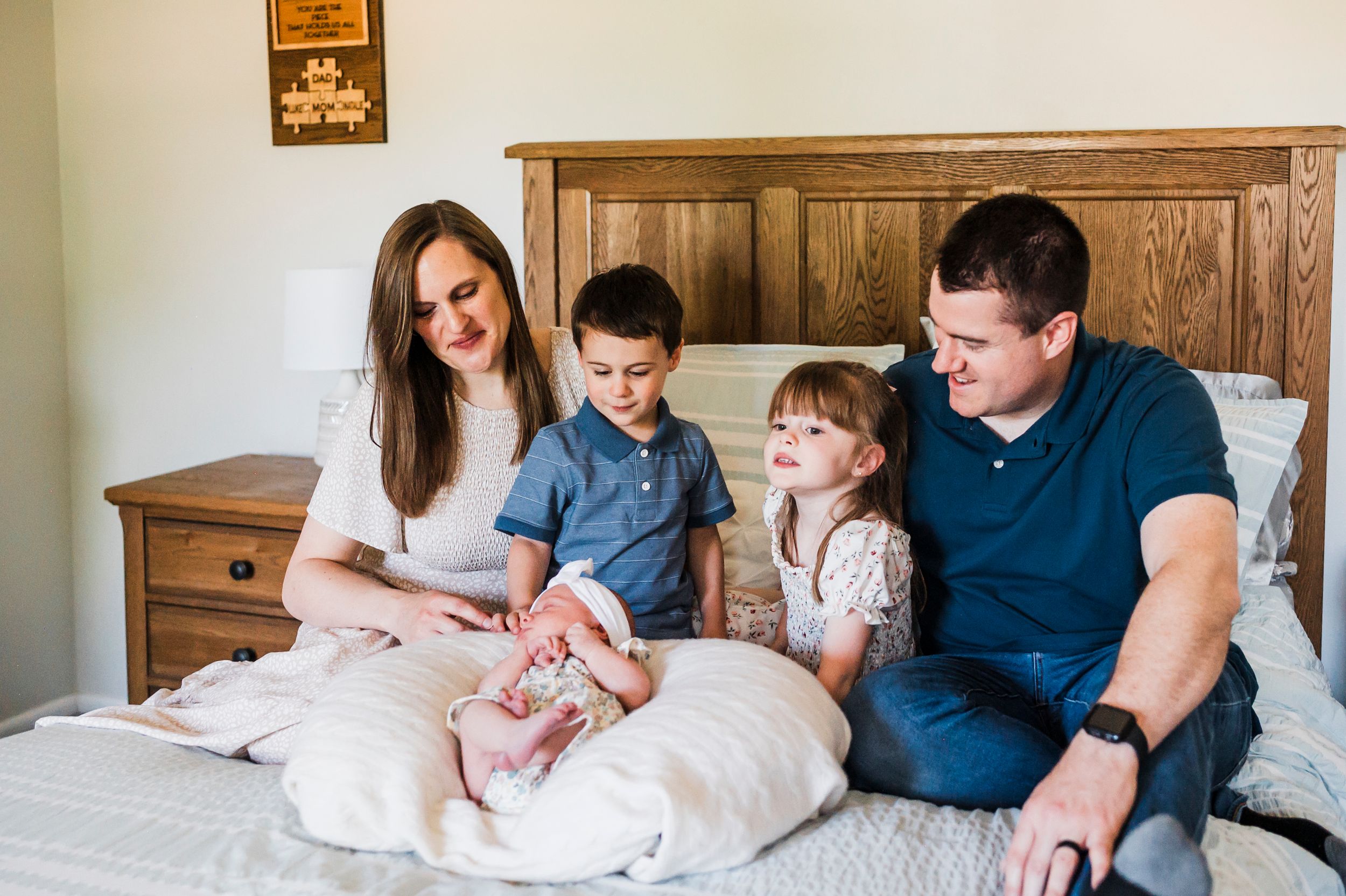 A family sits together on a wooden headboard bed, creating a cozy moment at home.