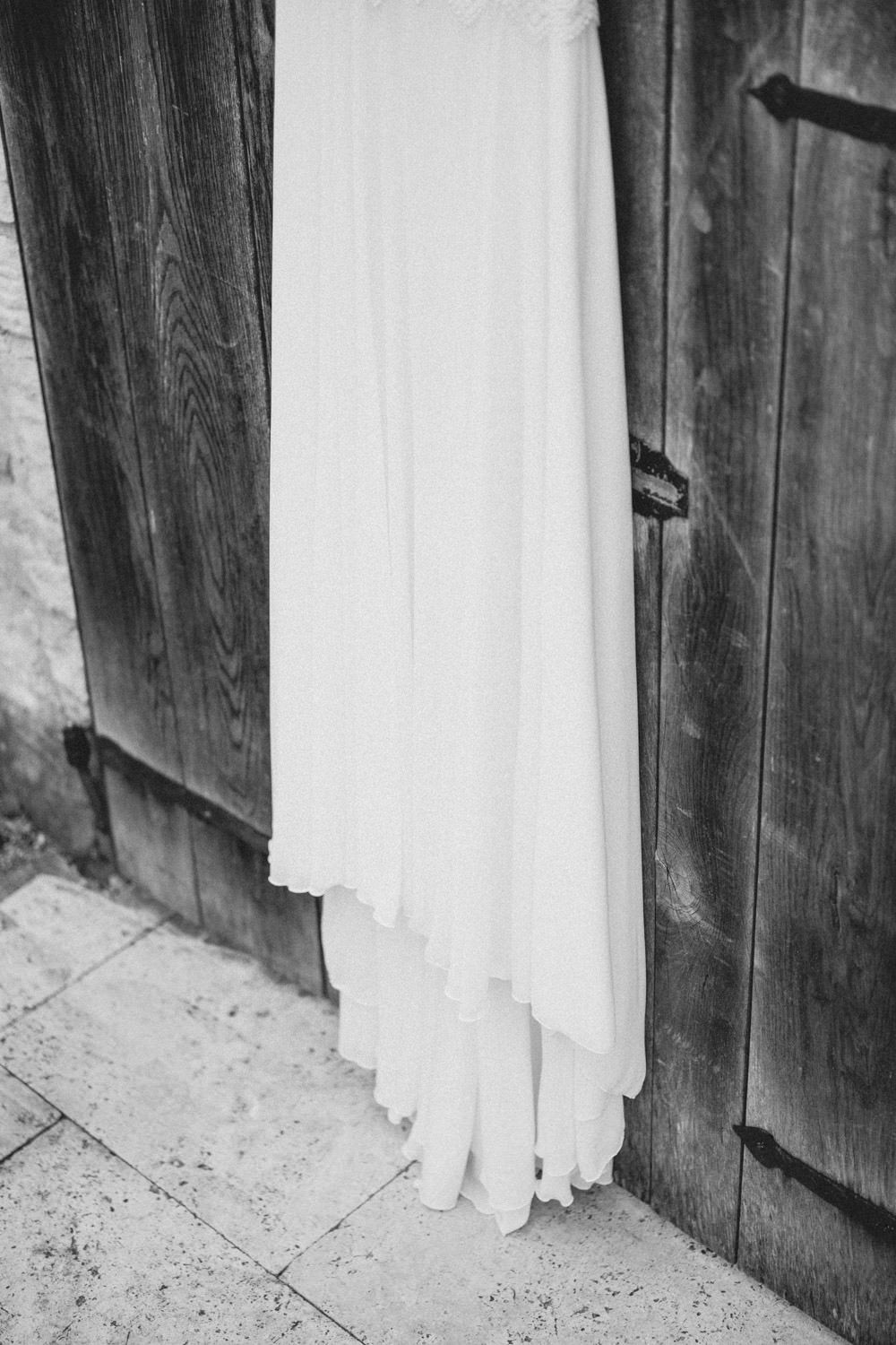 Black and white image of a flowing wedding dress against vintage wooden doors.