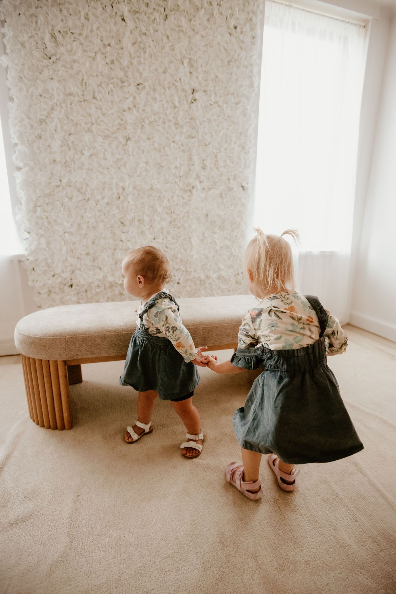 Small child in patterned outfit exploring interior room with plants and natural lighting.
