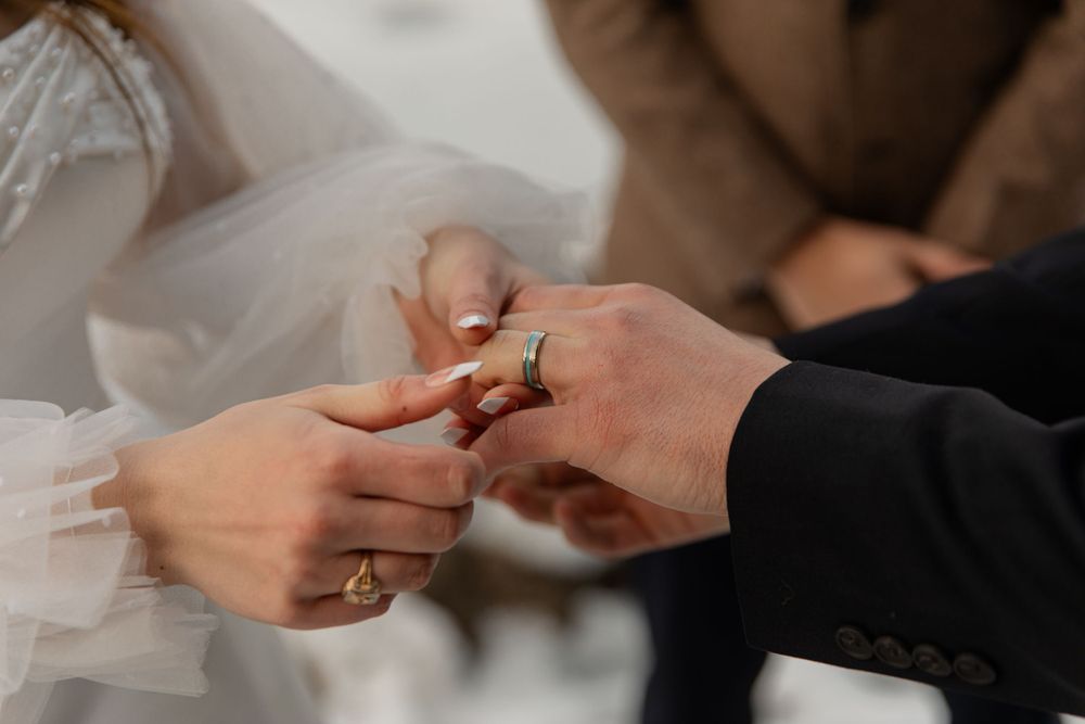 Close-up of ring exchange during winter wedding ceremony.