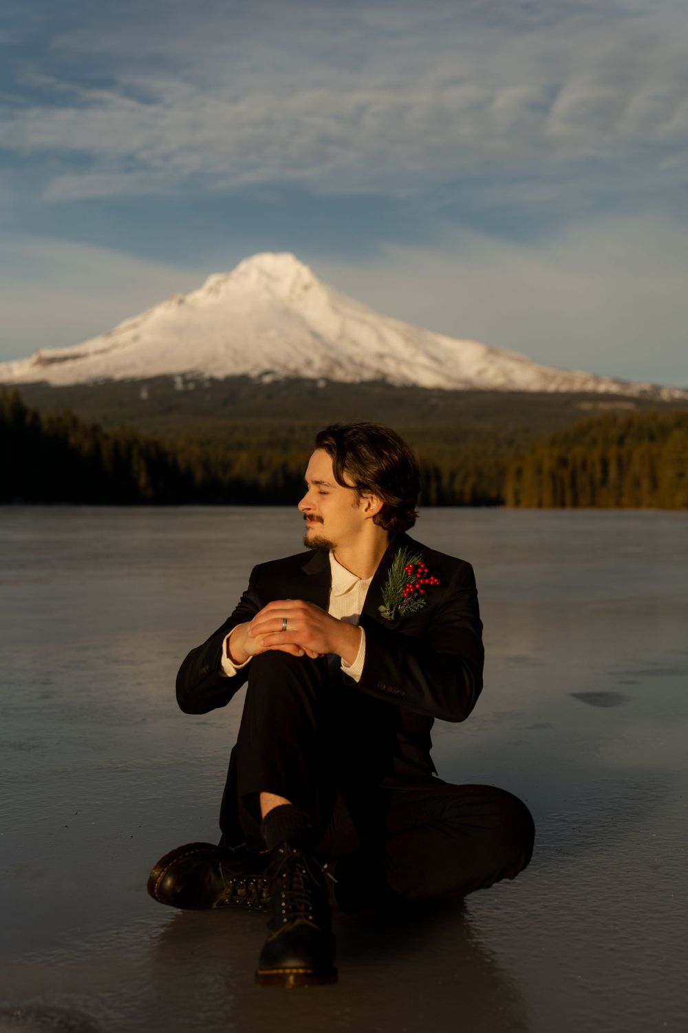 Snow-capped mountain peak rises majestically over a frozen lake during golden hour.