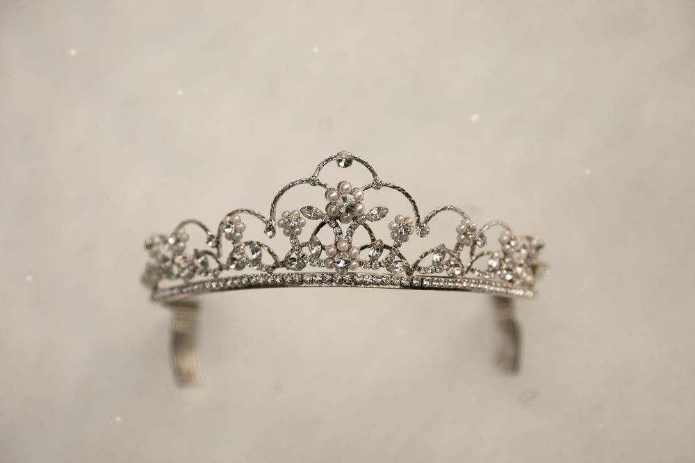 Delicate silver tiara with intricate crystal details against light background.