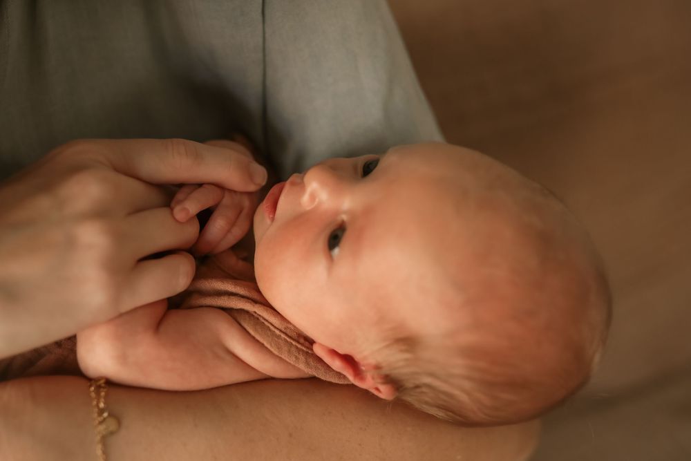 A newborn baby resting peacefully in an adult's gentle hands, with soft natural lighting highlighting delicate features.