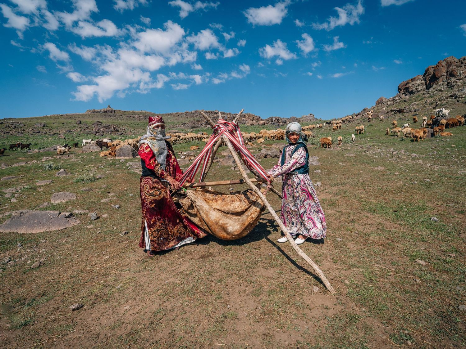 Qashqai women churning doogh with a traditional mashk on the slopes of Mount Sabalan, Iran.