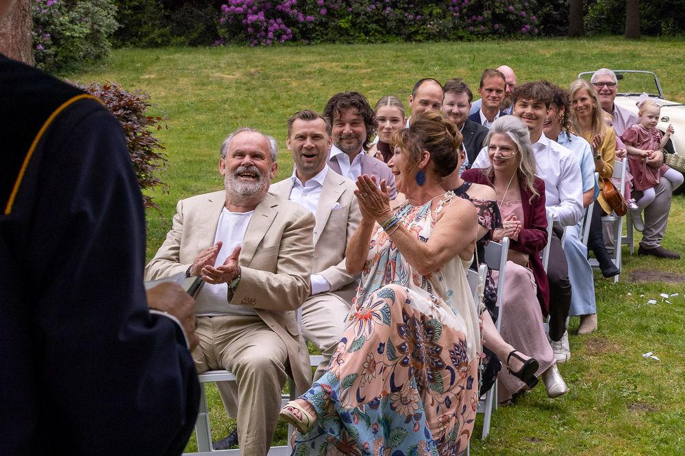 Gasten klappen lachend tijdens ceremonie  - documentaire bruidsreportage aan huis - Teteringen in eigen achtertuin - MaxFotos