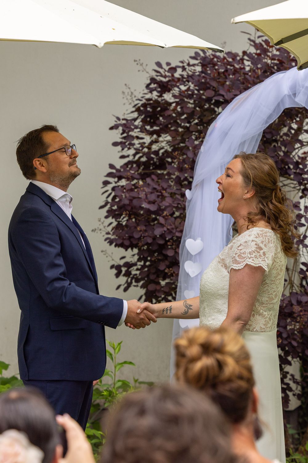 Bruidspaar lacht uitbundig naar elkaar tijdens ceremonie - documentaire bruidsreportage aan huis - Teteringen in eigen achtertuin - MaxFotos