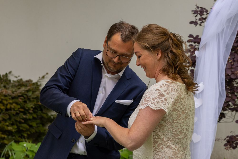 Bruidspaar kijkt lachend naar ringen  - documentaire bruidsreportage aan huis - Teteringen in eigen achtertuin - MaxFotos