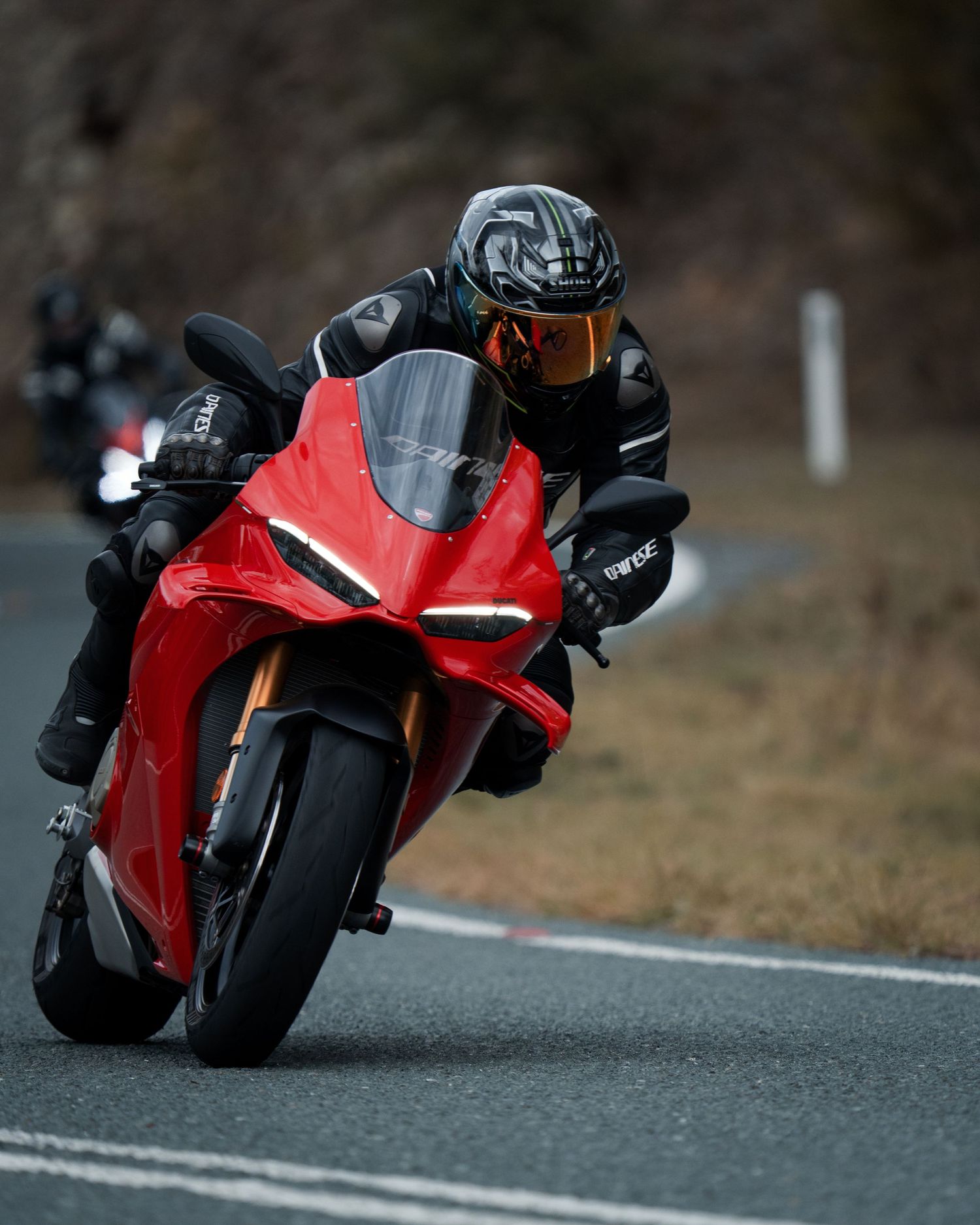 Rider leaning a red Ducati superbike into a curve on a winding road.